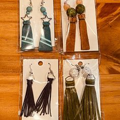 four pairs of earrings in plastic packaging on a wooden table with beads and tassels