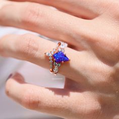 a woman's hand with a ring on it and a blue stone in the middle