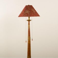 a lamp that is sitting on top of a wooden table with a red shade over it