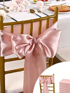 a pink chair sash is tied to the back of a gold chiavard and sits on a white table