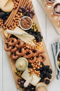 a cheese board with pretzels, grapes, nuts and other foods on it