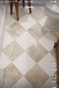 a white toilet sitting inside of a bathroom next to a wooden table and chair on top of a tiled floor