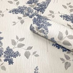 a blue and white wallpaper with flowers on it's side, next to a bed sheet