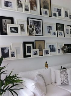 a white couch sitting in front of a wall with pictures on it's sides