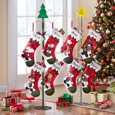 christmas stockings hanging from a pole in front of a christmas tree with presents on the floor