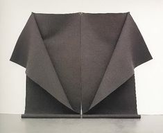 an origami sculpture made out of black paper on top of a white table