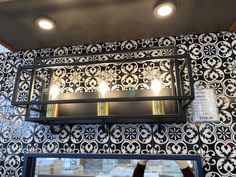 a light fixture hanging from the ceiling above a mirror in a room with black and white wallpaper