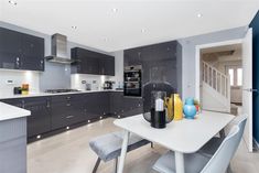 a modern kitchen with grey cabinets and white counter tops is seen from the dining room