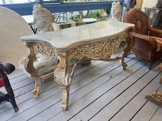 an old table and chairs are on the porch with other antique furniture in the background