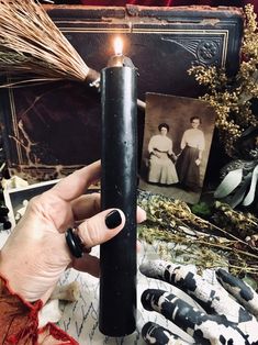 a person holding a lit candle in front of an old photo and other antique items