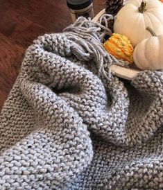 a knitted blanket sitting on top of a wooden floor next to a plate with food