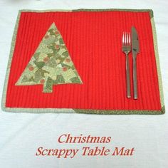 a placemat with a christmas tree on it next to a fork, knife and glass vase