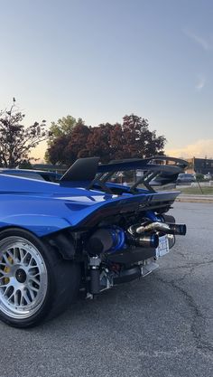 a blue sports car parked in a parking lot with its hood up and engine out