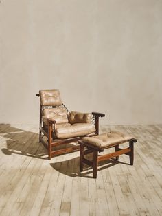 a reclining chair and footstool sitting on a wooden floor in front of a white wall