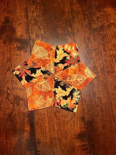 an orange and black square with leaves on it sitting on top of a wooden floor