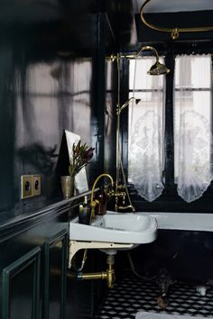 a bathroom with black and white checkered flooring, gold faucet, sink and mirror