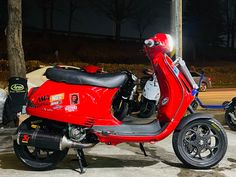 a red motor scooter parked on the street at night