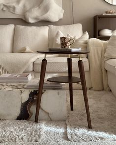 a coffee table sitting on top of a white rug in front of a living room couch