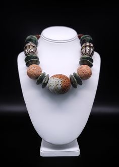 "Description and Details  A symphony of 27 unique beads, each one interesting on its own, blended into a statement of complementary color, form, and texture. The middle stone is an oversized carved two-colored jade longevity beads surrounded by large aventurine spacers, carved wooden longevity beads, Tibetan Silver, and gilt beads, smaller carved Jade longevity beads, natural turquoise beads, more jade, and finally a sterling silver box clasp with an inlaid tiger eye stone. This piece is a conve Elegant Jade Jewelry With Large Beads, Elegant Carved Agate Jewelry, Unique Green Carved Necklace, Green Carved Necklaces For Healing, Green Carved Healing Necklace, Traditional Jade Beaded Necklaces, Healing Green Carved Necklaces, Healing Green Carved Necklace, Carved Jade Round Bead Necklace