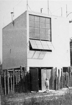 an old black and white photo of a man standing in front of a tall building