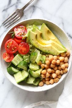 a bowl filled with avocado, chickpeas and tomatoes