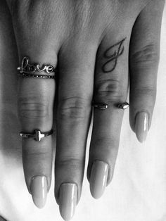 a woman's hand with three different rings on it and the word love tattooed on her finger