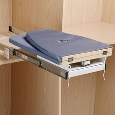 an open drawer in a wooden cabinet with a laptop on it's back end