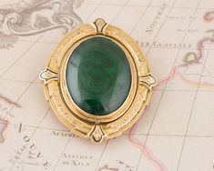 This incredible double sided brooch has a pin to allow either the green malachite stone to show or the gray blue agate. This versital pin has a rich dark green cabochon cut bezel set malachite on one side and a misty gray cabochon cut agate on the other side. The pin spins smoothly to switch to the other side. This brooch has some dents on the back from its age, which are pictured above. I love the carefully crafted metal work and milgrain on the metal frame.  Normal Price: $1,295.00 Metal Type: Antique Green Gemstone Brooches, Green Gemstone Pendant Brooches, Green Oval Brooches For Formal Occasions, Oval Green Brooch Jewelry, Misty Grey, Green Malachite, Malachite Stone, Wedding Brooch, Gold Stone