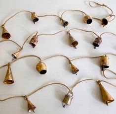 several bells hanging from a rope on a white surface