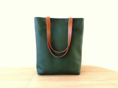 Large everyday casual vegan leather tote bag in forest green color with real leather handles. * Exterior: - High quality vegan/faux leather in beautiful intense dark green  color. * Interior: - Sandy beige ad white polka dot Italian natural cotton. * Two inside slip pockets for personal belongings like phone, keys, etc. * Real leather handles in dark chocolate brown/cognac brown/black attached with antique toned brass rivets * Closes with magnetic snap closure reinforced with natural leather * Additionally lined for better structure. Measurements: Height: 15 inches Width of the bag: 13 inches Width of the bottom: 3.5 inches Green Leather-lined Tote Shoulder Bag, Dark Green Satchel Shoulder Bag For Daily Use, Green Satchel Bag With Rolled Handles, Green Leather Everyday Bags, Modern Olive Shoulder Bag For Everyday, Everyday Green Leather Bag, Modern Olive Bags For Everyday Use, Green Shoulder Bag With Rolled Handles For Travel, Green Shoulder Bag With Rolled Handles For Everyday Use