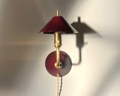 a lamp that is on the wall next to a light fixture with a red shade