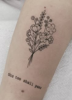 this too shall pass tattoo on the left arm is shown with flowers and words in black ink