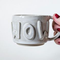 a woman holding a coffee cup with the word joy on it's side, in front of a white background