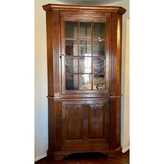 a wooden china cabinet with glass doors on the top and bottom, against a wall