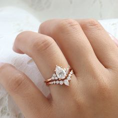 a woman's hand with two diamond rings on top of her finger and the ring has three smaller diamonds in it