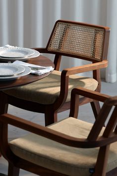 a wooden chair sitting next to a table with plates and silverware on top of it