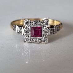 Art deco 18CT, platinum panel ring with Ruby and diamonds. Beautiful princess cut ruby 3.5mm surrounded by eight diamonds. The ornate setting of platinum panel, the design that is so indicative of the 1920's, leading into the shoulders the design continues with a single diamond on each side. Size- UK- M US- 6.5 Hallmark- 18CT&PLAT (18CT gold and platinum) The item will be packaged in a leatherette ring box using royal mail special delivery. All of my pieces are offsite in secure storage and will Vintage Red Diamond Ring With Halo Setting, Vintage Ruby Rings With Single Cut Diamonds, Art Deco Ruby Ring With Diamond Details, Vintage Ruby Ring With Diamond Accents, Art Deco Ruby Ring For Formal Occasions, Red Victorian Diamond Ring, Art Deco Ruby Ring With Diamond Cut For Wedding, Vintage Ruby Rings With Diamond Accents, Vintage Ruby Ring With Diamond Accents For Promise