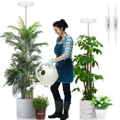 a woman in an apron is holding a watering can next to some potted plants