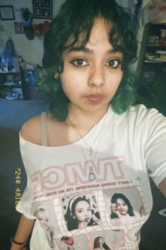 a woman with green hair wearing a white t - shirt and looking at the camera