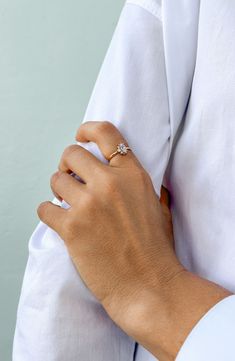 a woman's hand with a diamond ring on top of her arm, wearing a white shirt