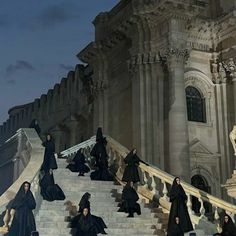 a group of people in black robes walking up some stairs with their backs to the camera