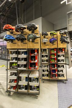 several different types of helmets are on display in a bike shop, with shelves full of them