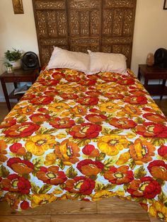 a bed with an orange and yellow flowered bedspread on top of it