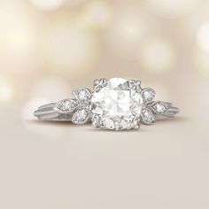 an oval diamond ring with leaves on the side and diamonds in the middle, set against a neutral background