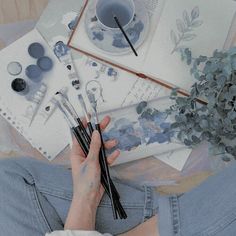 a person sitting on the floor with some paint brushes and paints in front of them