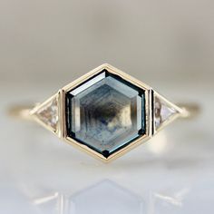 a close up view of an engagement ring with a blue and white diamond in the center