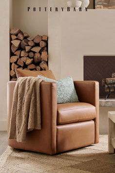 a brown chair sitting in front of a fire place next to a pile of logs