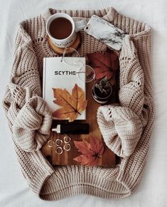 the contents of a cozy fall outfit laid out on a bed with coffee and other items