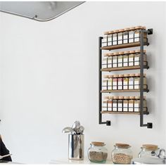 a wall mounted spice rack on the side of a white wall next to a sink