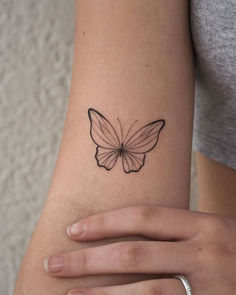 a woman's arm with a small butterfly tattoo on the back of her arm